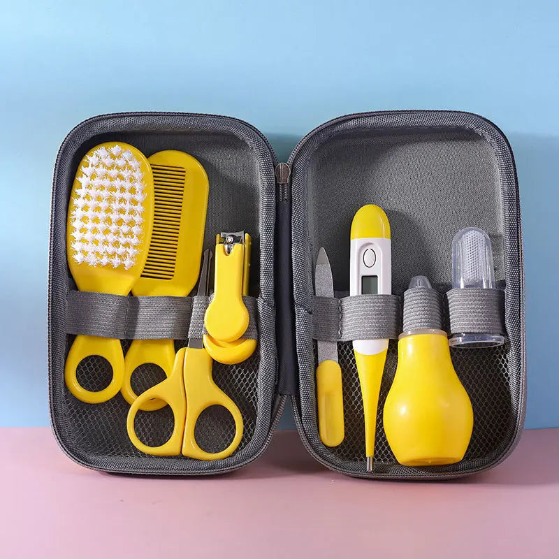A Baby Care Kit containing a nasal suction device, toothbrush, hair brush, body heat detector, nail clipper, scissors, comb, and nail file, all in pink color, displayed in an open gray case with a blue background.