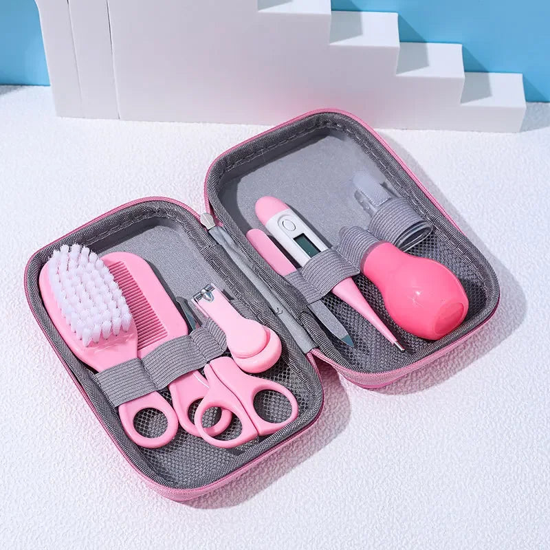 A Baby Care Kit containing a nasal suction device, toothbrush, hair brush, body heat detector, nail clipper, scissors, comb, and nail file, all in pink color, displayed in an open gray case with a blue background.