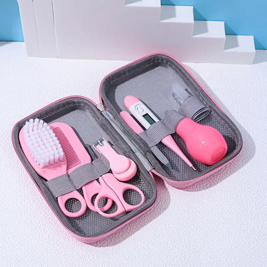A Baby Care Kit containing a nasal suction device, toothbrush, hair brush, body heat detector, nail clipper, scissors, comb, and nail file, all in pink color, displayed in an open gray case with a blue background.