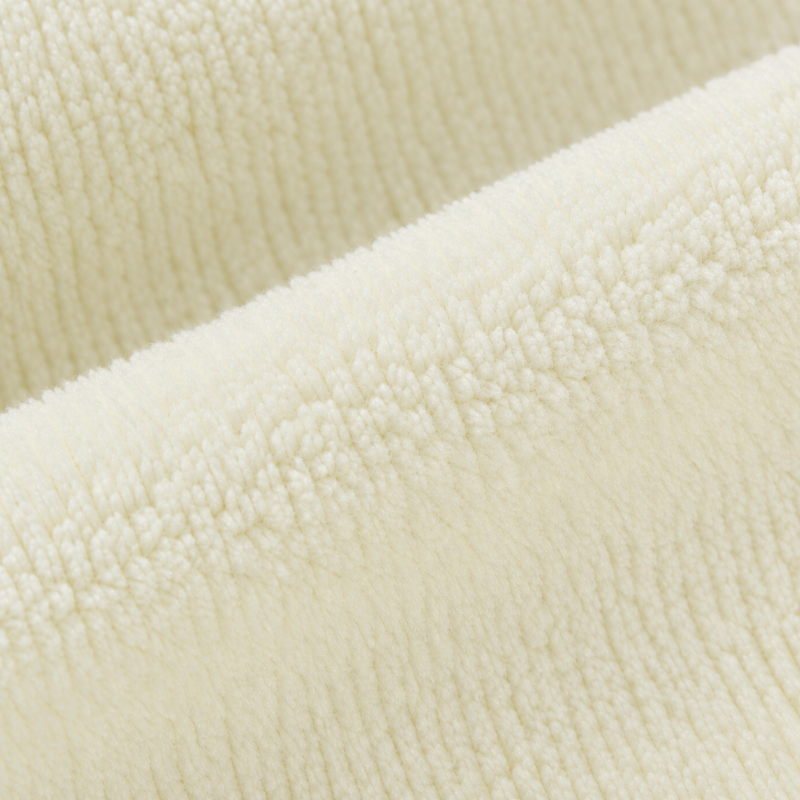 A close-up of a soft, plush fleece fabric in a warm cream or off-white color, showing the textured loop pile and folded layers.