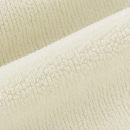 A close-up of a soft, plush fleece fabric in a warm cream or off-white color, showing the textured loop pile and folded layers.