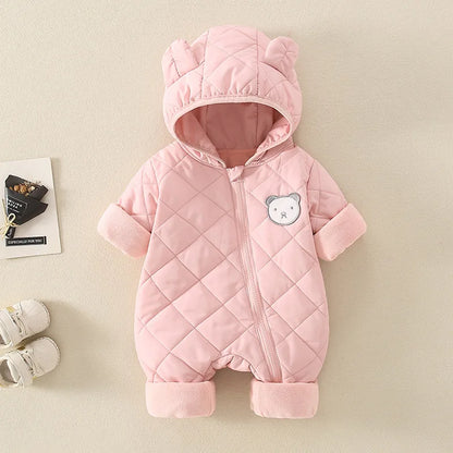 Pink quilted baby snowsuit with bear patch on a beige background
