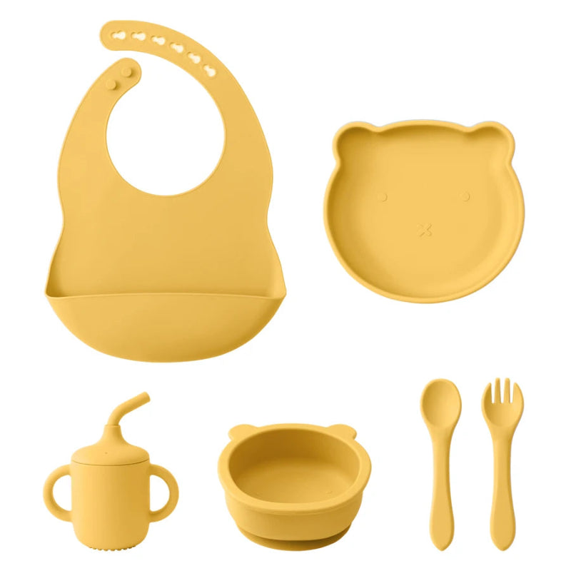 A set of baby feeding supplies in yellow, including a bib, plate, bowl, cup, and utensils with a suction base.