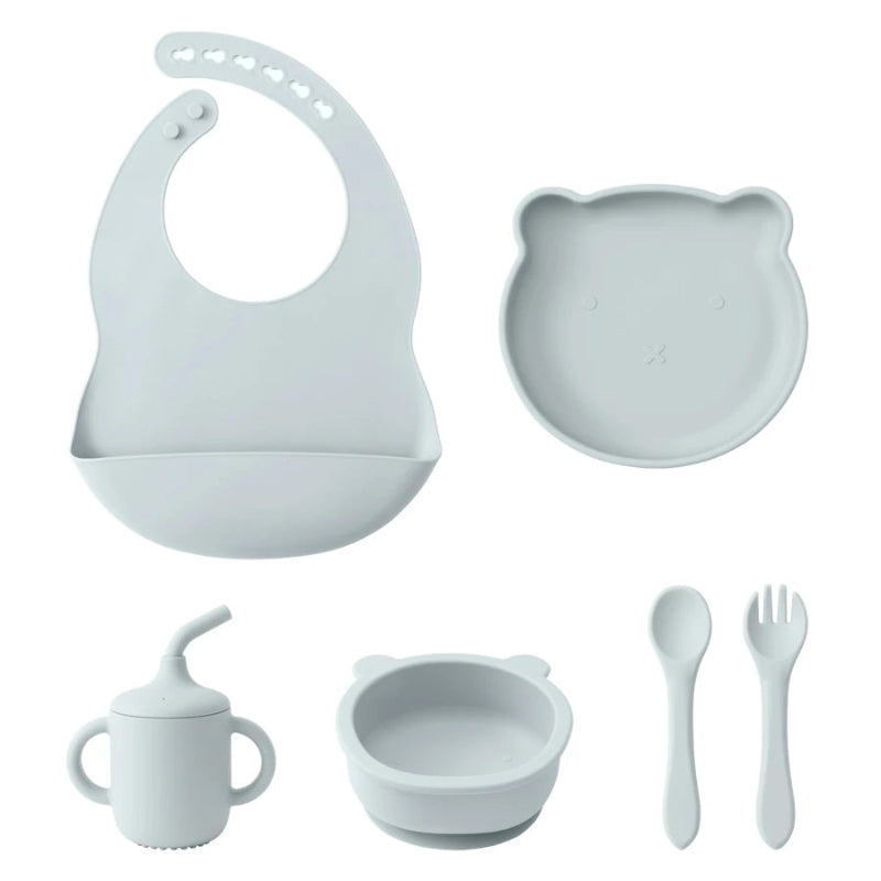 A set of baby feeding supplies in yellow, including a bib, plate, bowl, cup, and utensils with a suction base.