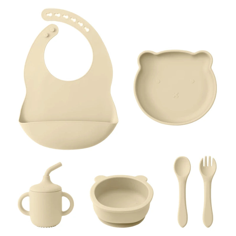 A set of baby feeding supplies in yellow, including a bib, plate, bowl, cup, and utensils with a suction base.