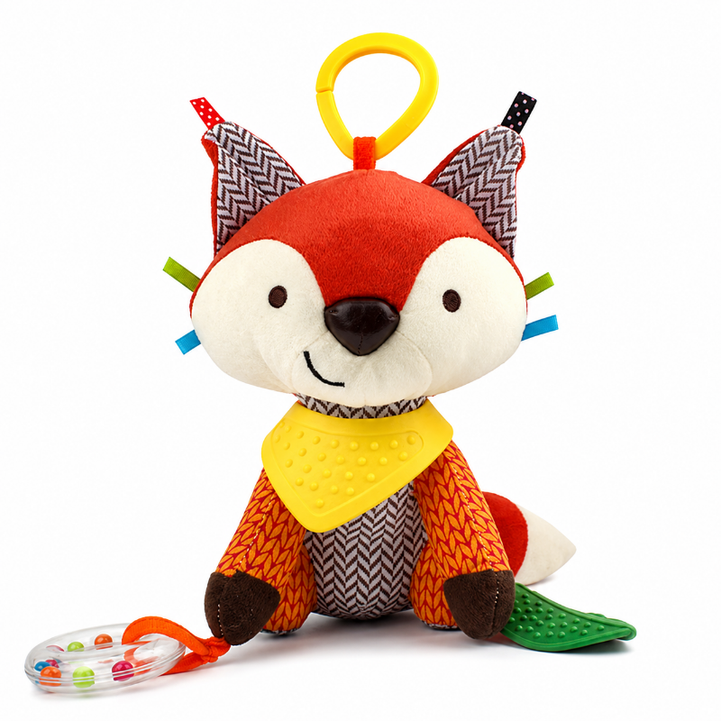 A plush toy fox with a red and cream face, orange and brown body, patterned fabric ears, a yellow loop on its head, a yellow bib, and a clear ring teether with colorful beads on a white background.