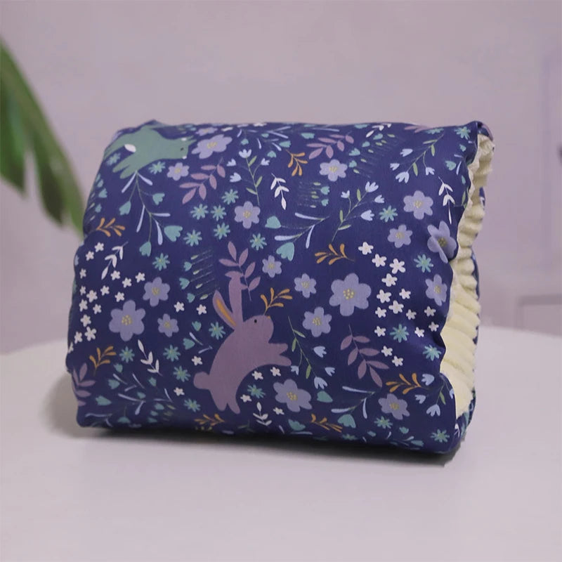 A multicolored nursing arm pillow with a pattern featuring animals and leaves.