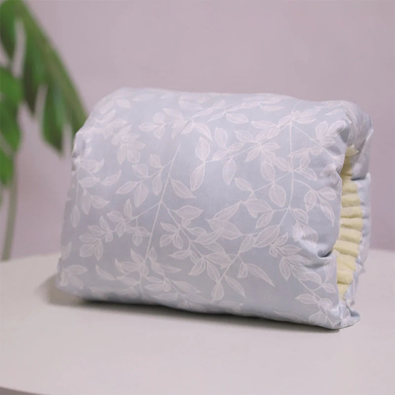 A multicolored nursing arm pillow with a pattern featuring animals and leaves.