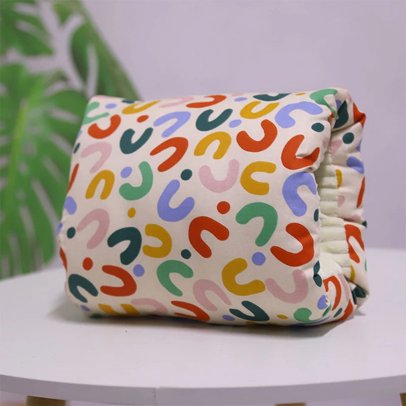 A multicolored nursing arm pillow with a pattern featuring animals and leaves.