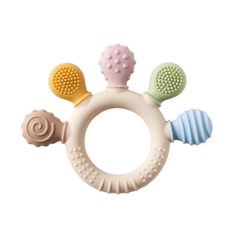Two silicone baby teether rings with various colorful textures, designed to be held by little hands, placed next to a plush toy on a soft surface.
