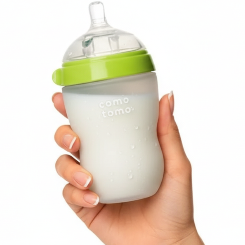 Hand holding a baby bottle with a green cap on a white background