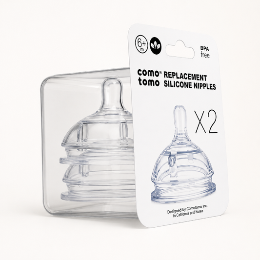 Two clear silicone baby replacement nipples in a transparent plastic case with a white retail card labeled 'como tomo replacement silicone nipples x2' on a light neutral background.