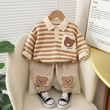 A set of baby boy clothing featuring a striped green and beige polo shirt with a bear cartoon design, paired with beige pants with bear patches, displayed on a mannequin.