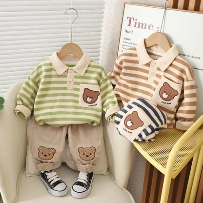 A set of baby boy clothing featuring a striped green and beige polo shirt with a bear cartoon design, paired with beige pants with bear patches, displayed on a mannequin.