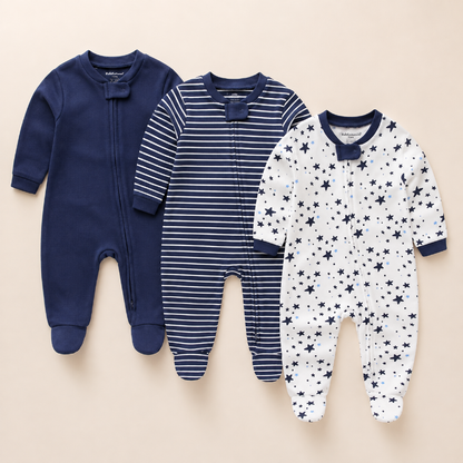 Three baby footed sleepers laid flat on a light beige background. The left sleeper is solid navy blue.