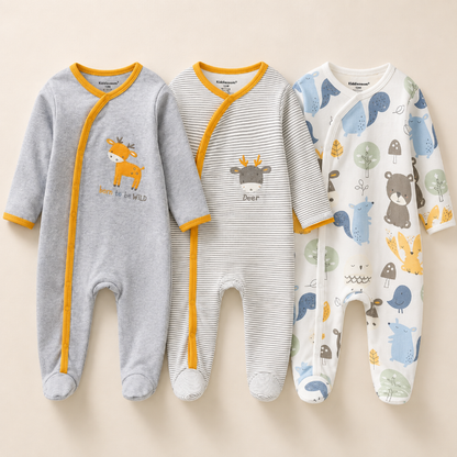 Three baby footed sleepers laid flat on a light beige background. The left sleeper is heather gray with mustard yellow trim and a deer graphic.
