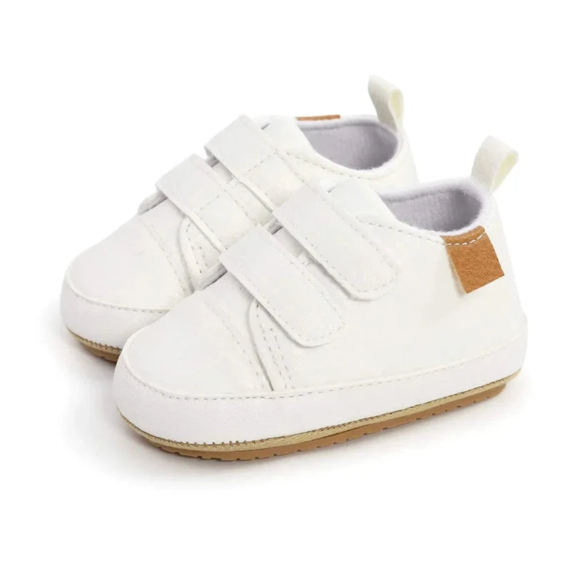 A pair of beige baby sneakers with hook and loop closure and a non-slip sole, designed for comfort and ease of wear for young children.