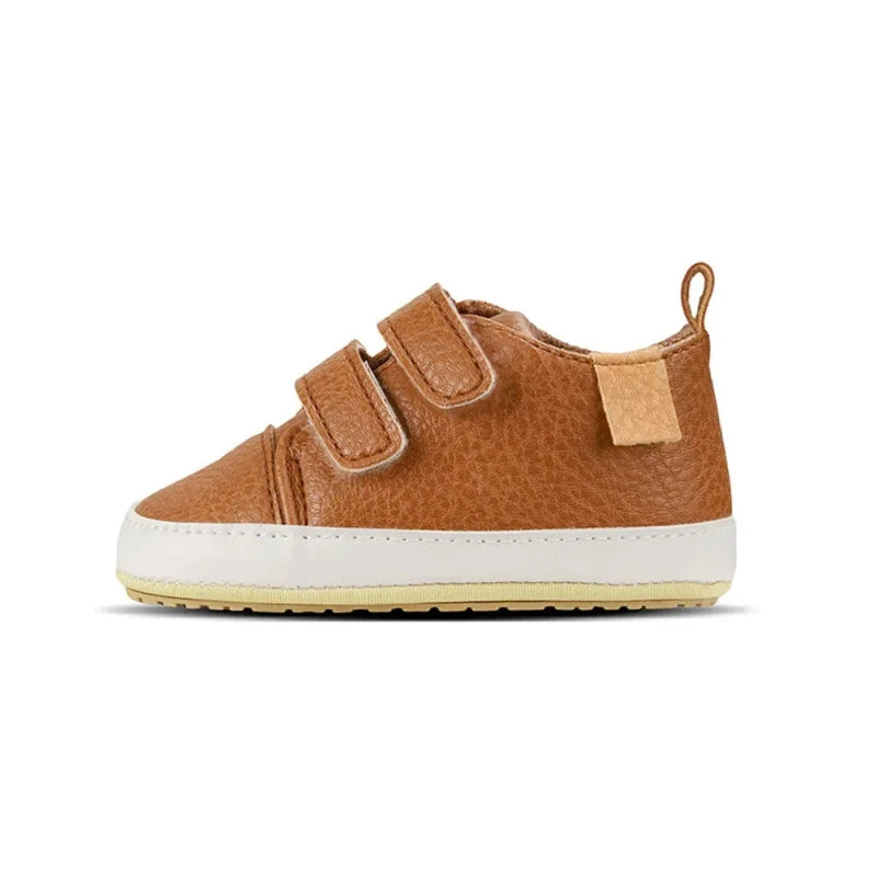 A pair of beige baby sneakers with hook and loop closure and a non-slip sole, designed for comfort and ease of wear for young children.
