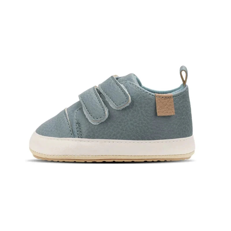 A pair of beige baby sneakers with hook and loop closure and a non-slip sole, designed for comfort and ease of wear for young children.
