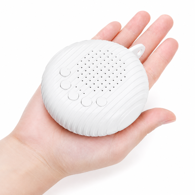 A small white portable speaker with a ribbed oval body, four round buttons, and a perforated front grille, shown resting on an open hand against a plain white background.